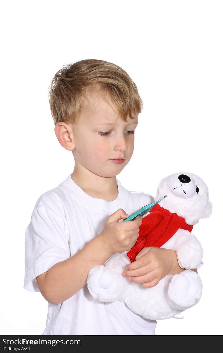 Cute young boy using a thermometer on his stuffed bear. Cute young boy using a thermometer on his stuffed bear