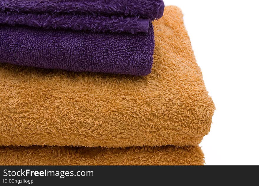 A stack of yellow and purple bath towels against a white background