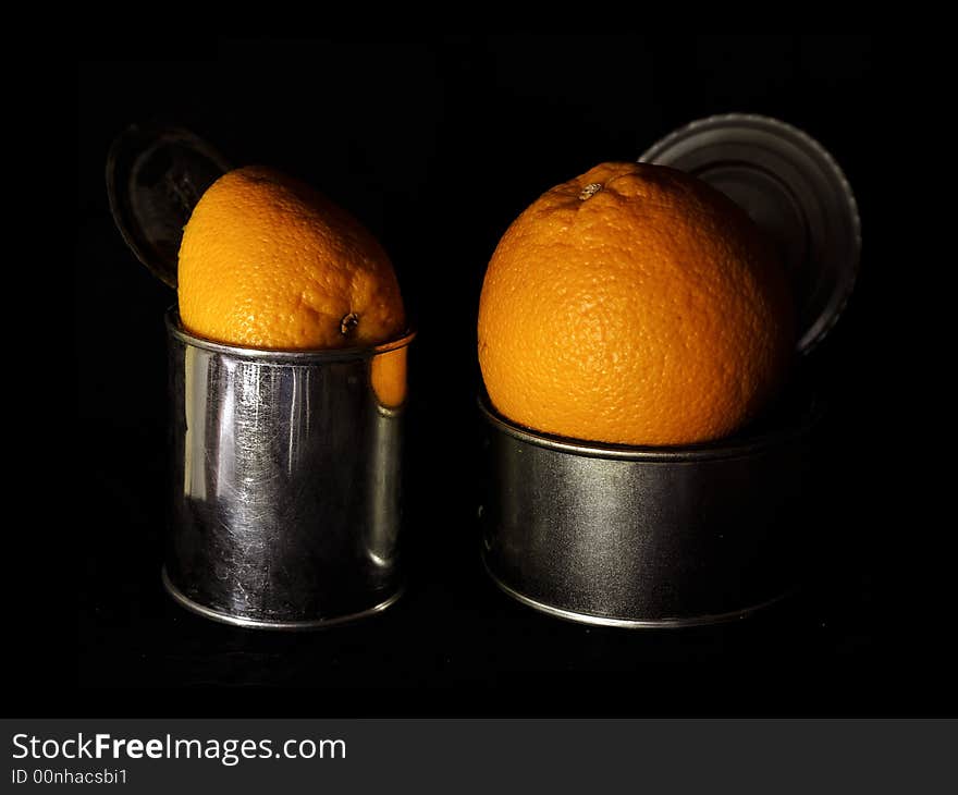 Oranges in cans over black background. Oranges in cans over black background