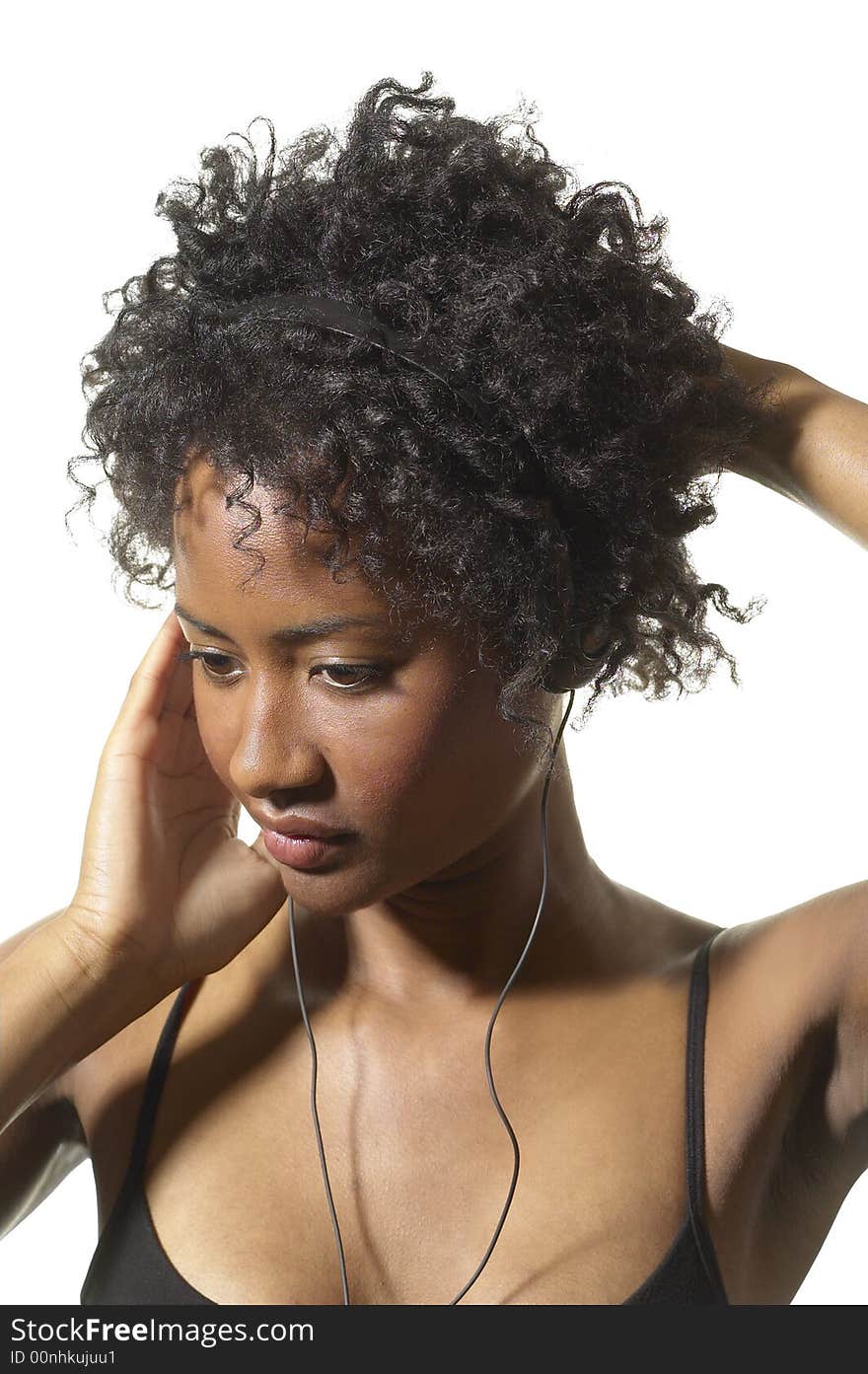 African American woman holds her music head phones and just the head phone against her ear. African American woman holds her music head phones and just the head phone against her ear.