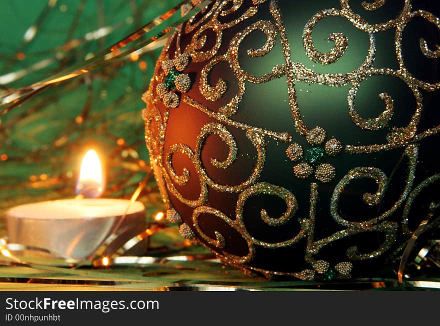 Christmas candle and ball with gold ornament on a green background. Christmas candle and ball with gold ornament on a green background