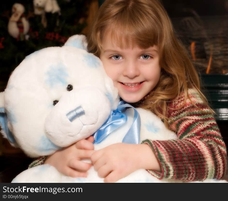 Young elementary girl hugging a giant blue and white Teddy bear at Christmas time. Young elementary girl hugging a giant blue and white Teddy bear at Christmas time.