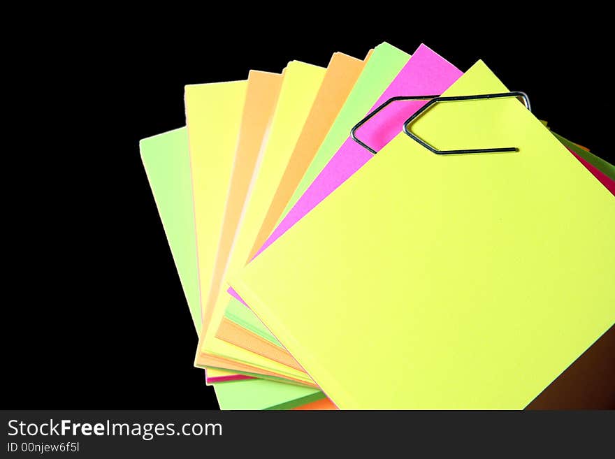 Colored paper notes over black background and joined by clips