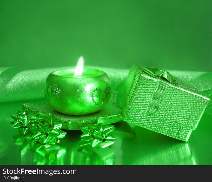 Green candle and gift box on celebration background