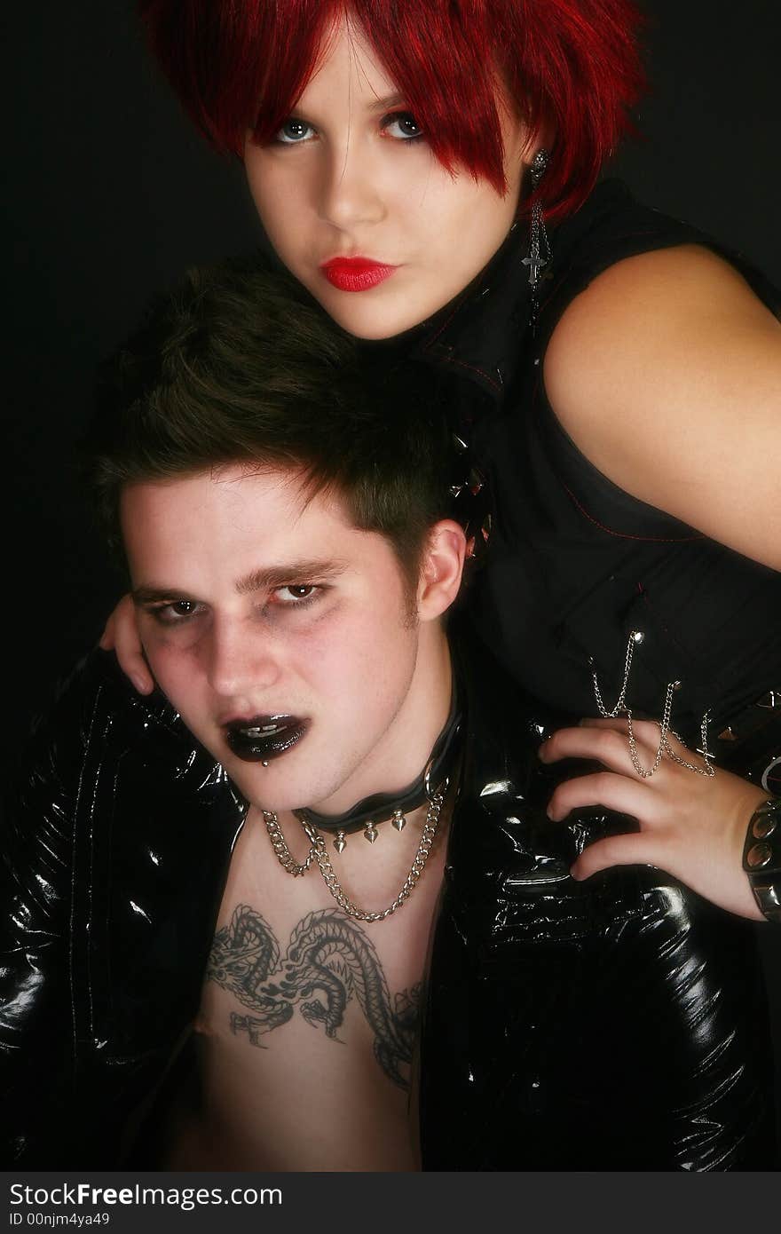 Young teen couple dressed in rocker wear over black. Young teen couple dressed in rocker wear over black.