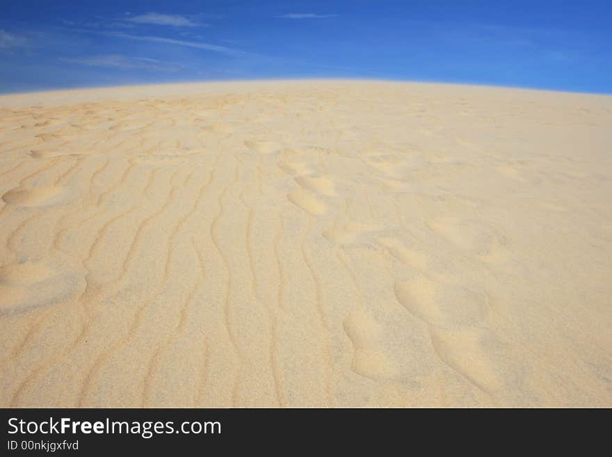 View of golden sand dunes against rich blue sky, clean versatile stock image