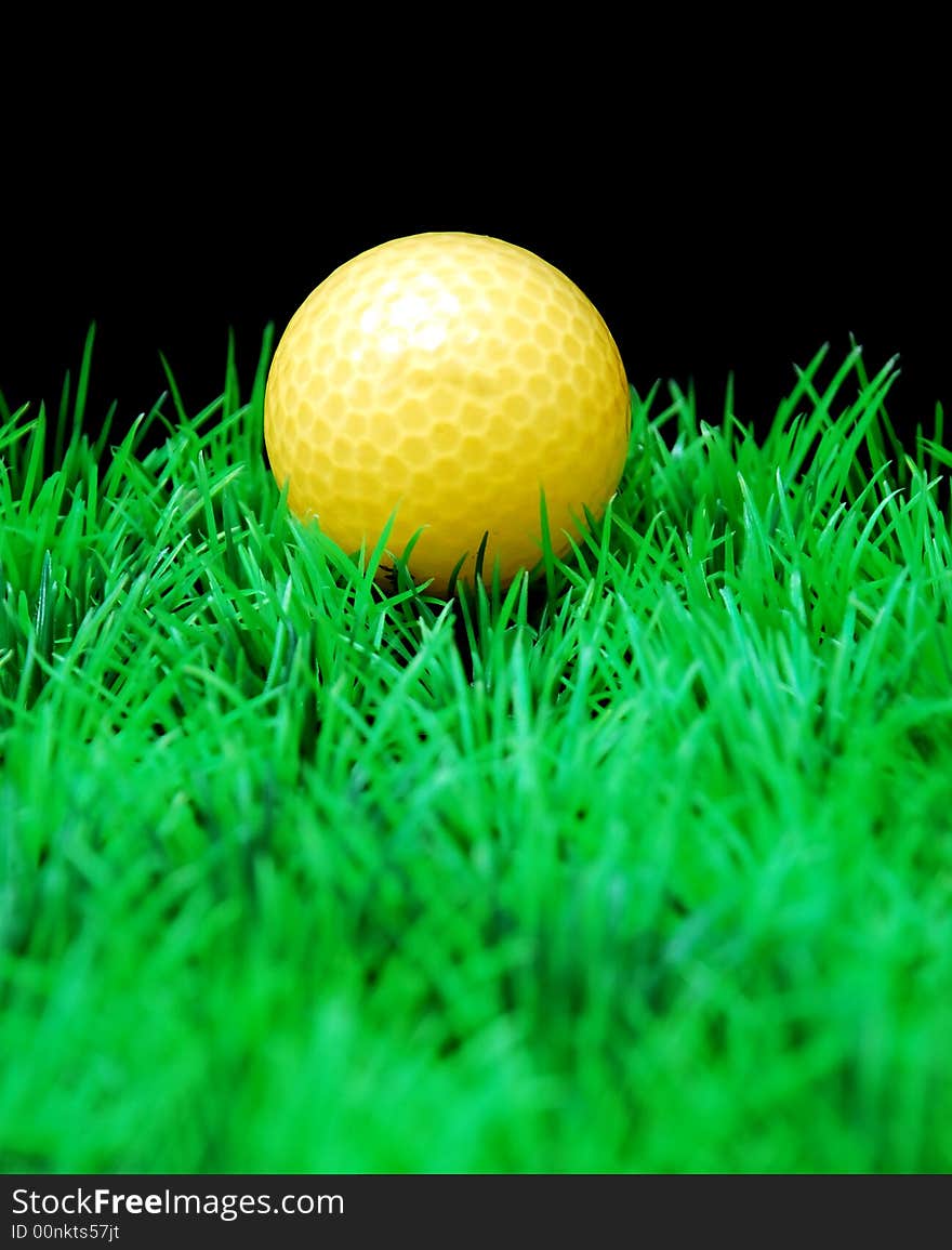 Golfball in orange tee, green fairway, isolated on black background