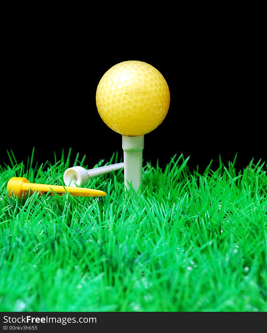 Golfball in white tee, green fairway, isolated on black background. Golfball in white tee, green fairway, isolated on black background