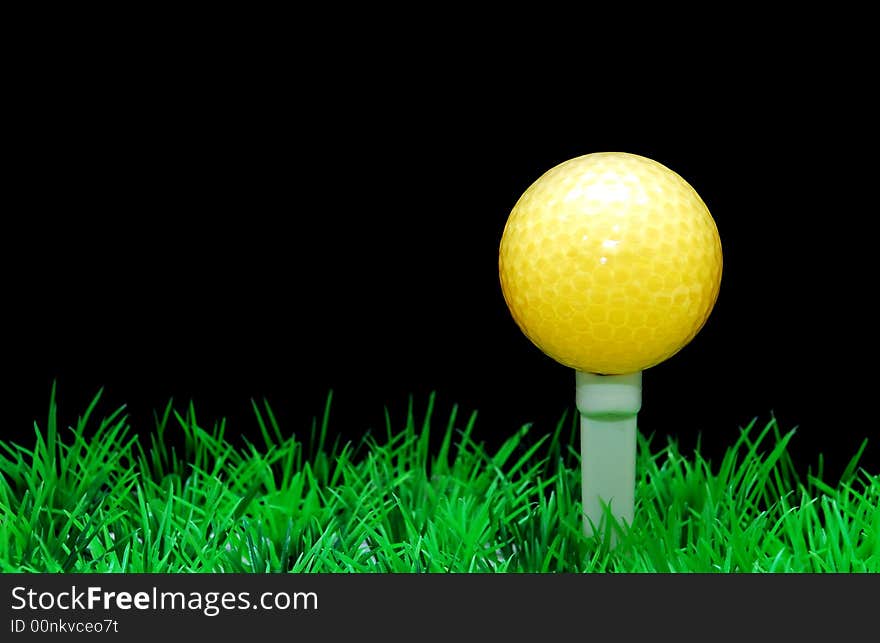 Golfball in white tee, green fairway, isolated on black background. Golfball in white tee, green fairway, isolated on black background