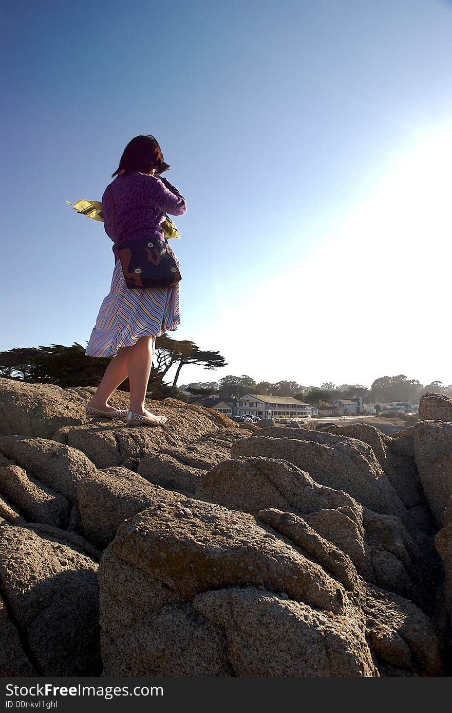 A woman standing on a rock with a blue sky background