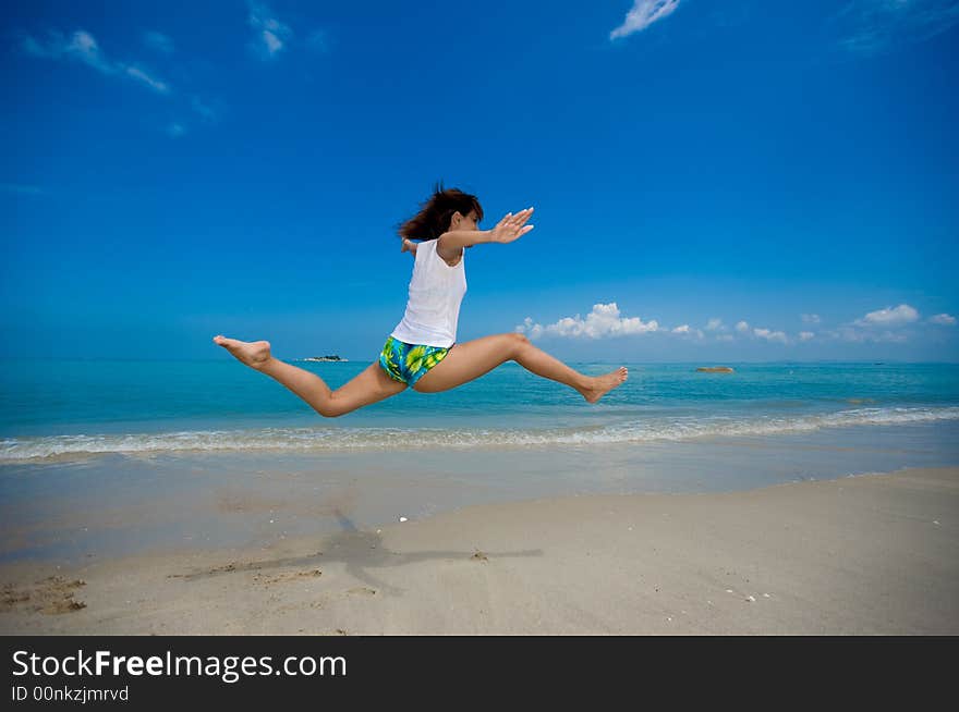 Young beautiful girl jumping happily at the beach. Young beautiful girl jumping happily at the beach