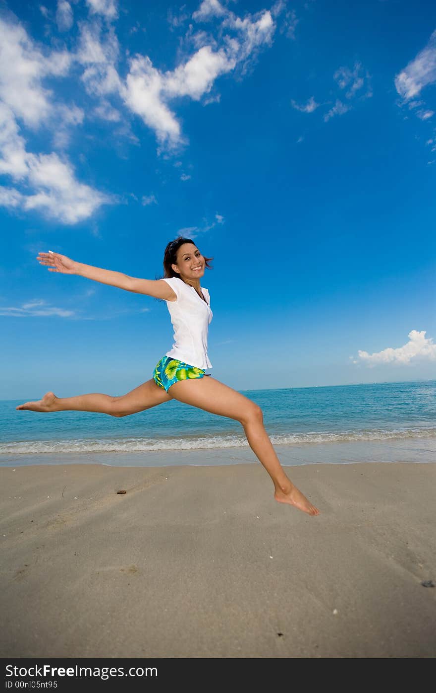 Young beautiful girl jumping happily at the beach. Young beautiful girl jumping happily at the beach