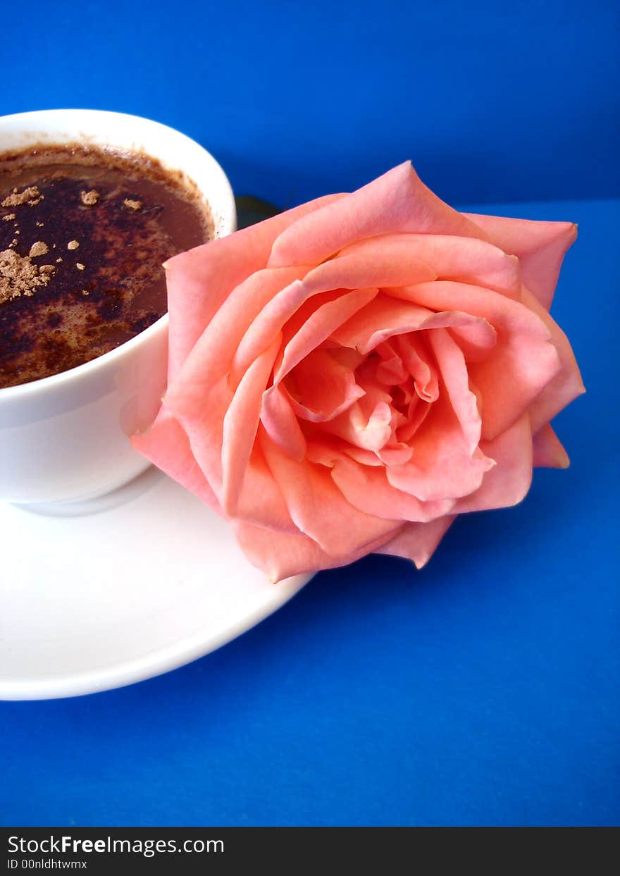 White cup of coffee with flower on blue background