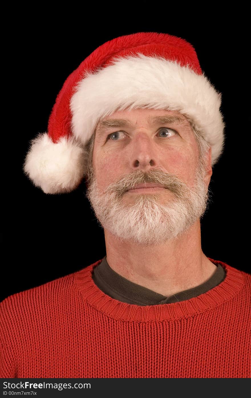 Pleasant middle-aged bearded man in a santa hat and red sweater over a black background. Pleasant middle-aged bearded man in a santa hat and red sweater over a black background