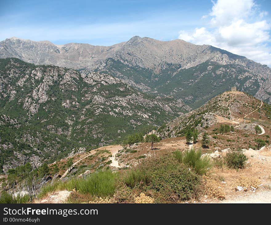 Immense mountains with a lot of green colours. The sky is lightblue and in the distance you can see a ruin on top of a mountain. Immense mountains with a lot of green colours. The sky is lightblue and in the distance you can see a ruin on top of a mountain.