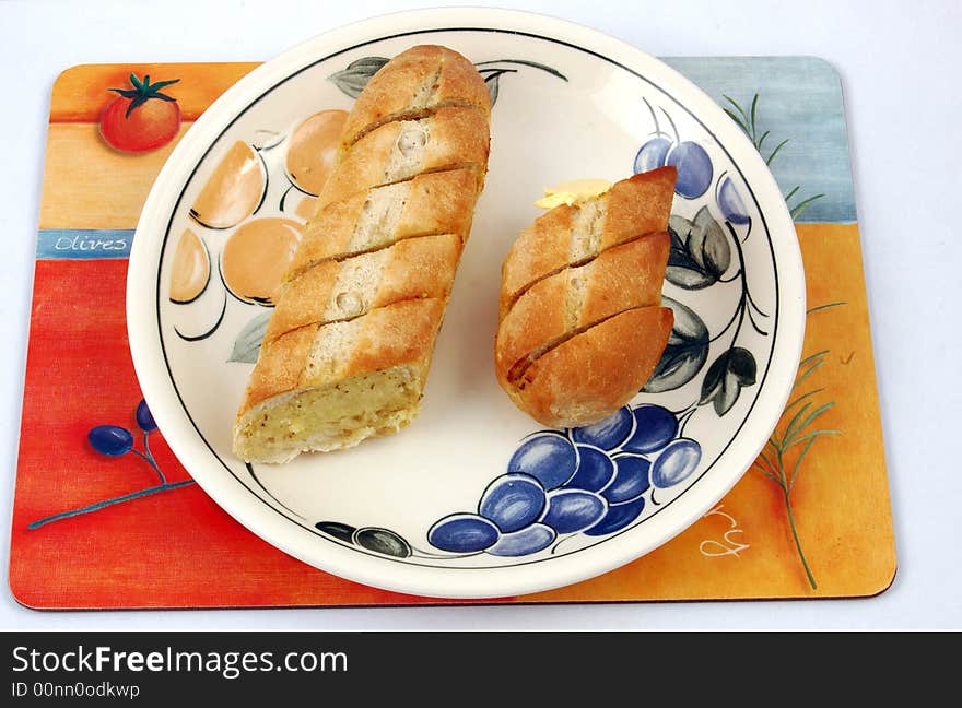 Garlic Bread on a plate on a mat.,Garlic bread is a kind of roasted or broiled bread that originates from Italy. The bread has a topping of garlic and butter or olive oil and at times even clarified butter is used.