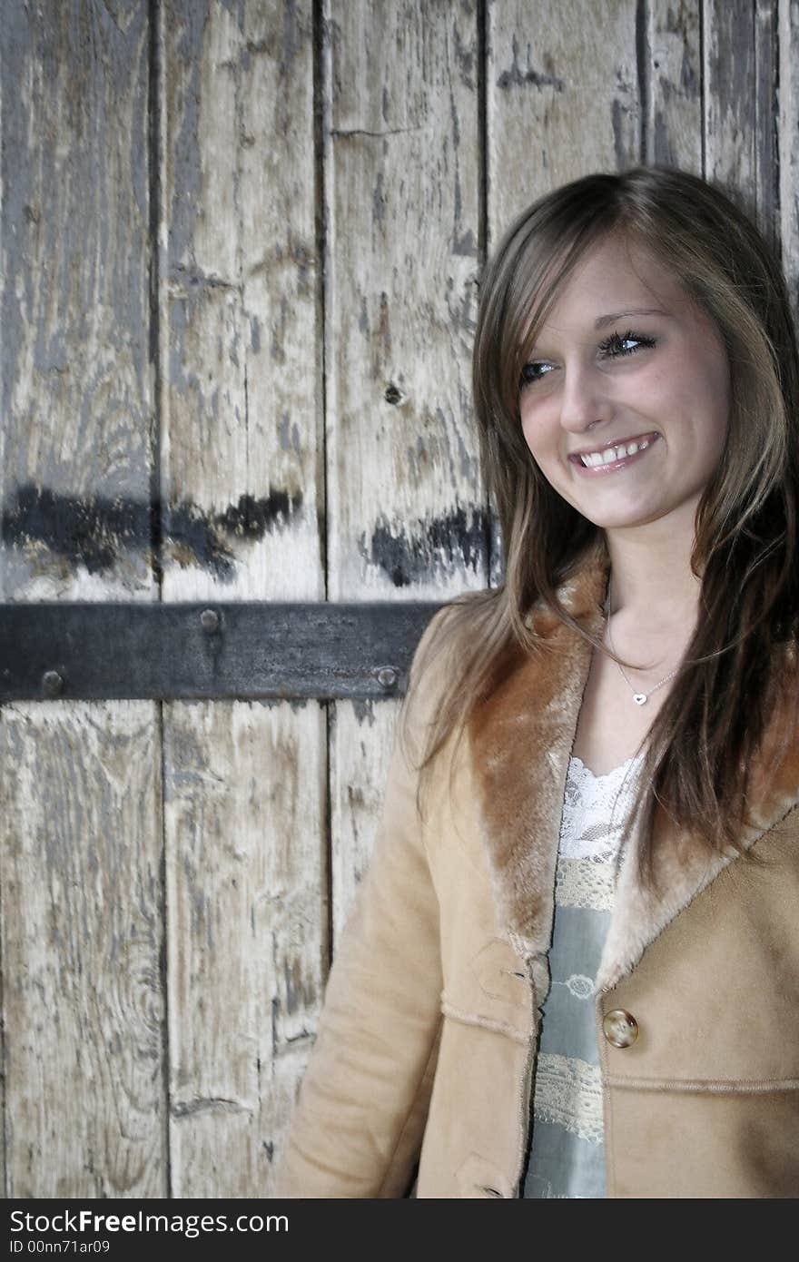 A young smiling, attractive woman with a rustic wood background. A young smiling, attractive woman with a rustic wood background