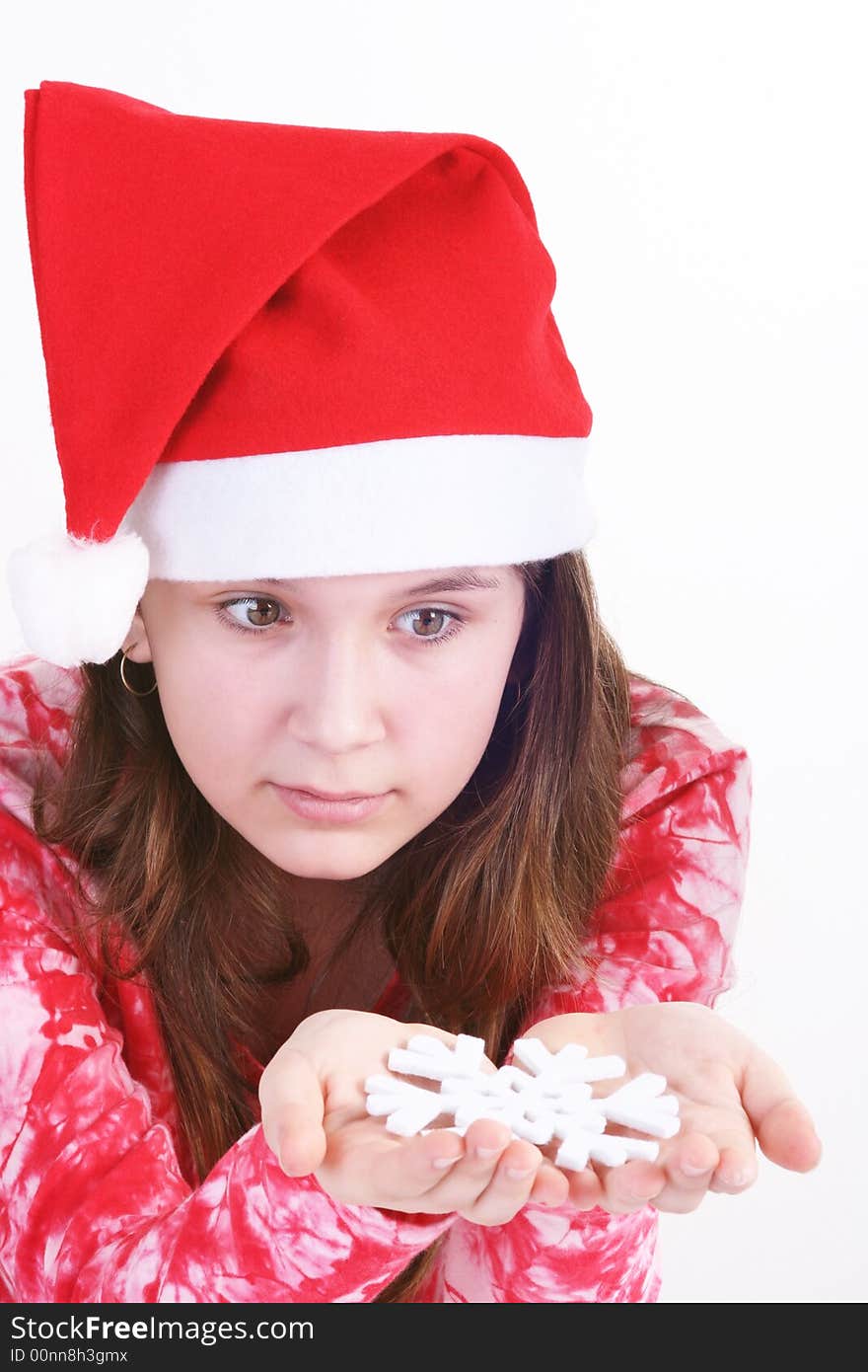 A portrait of a young teenager wearing a red Santa hat and red print top, holds out a large white snowflake in both hands in this studio setting. White background. A portrait of a young teenager wearing a red Santa hat and red print top, holds out a large white snowflake in both hands in this studio setting. White background.