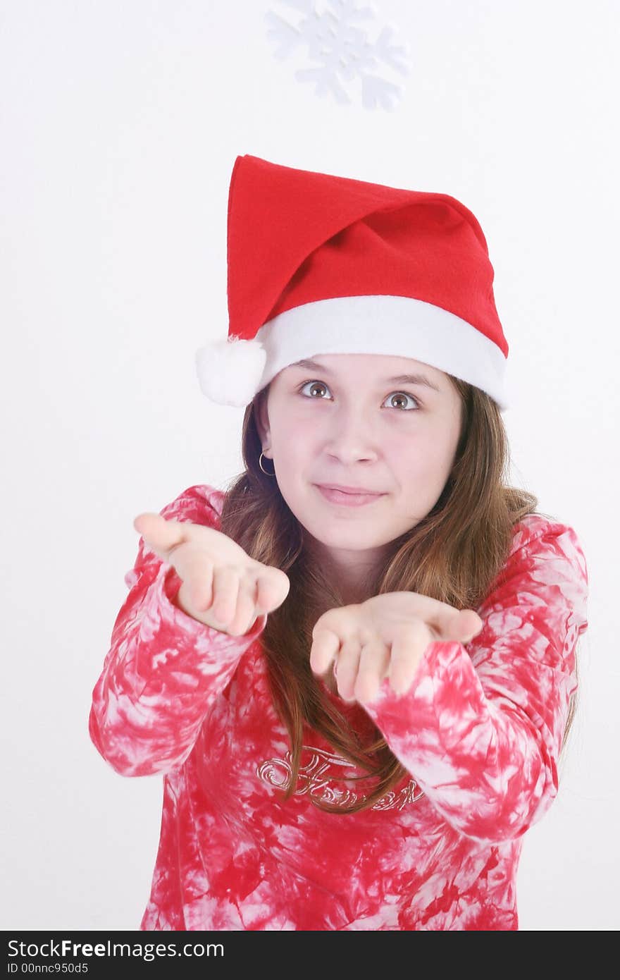 A portrait of a young teenager wearing a red Santa hat and red print top, holds out a large white snowflake in both hands in this studio setting. White background. A portrait of a young teenager wearing a red Santa hat and red print top, holds out a large white snowflake in both hands in this studio setting. White background.