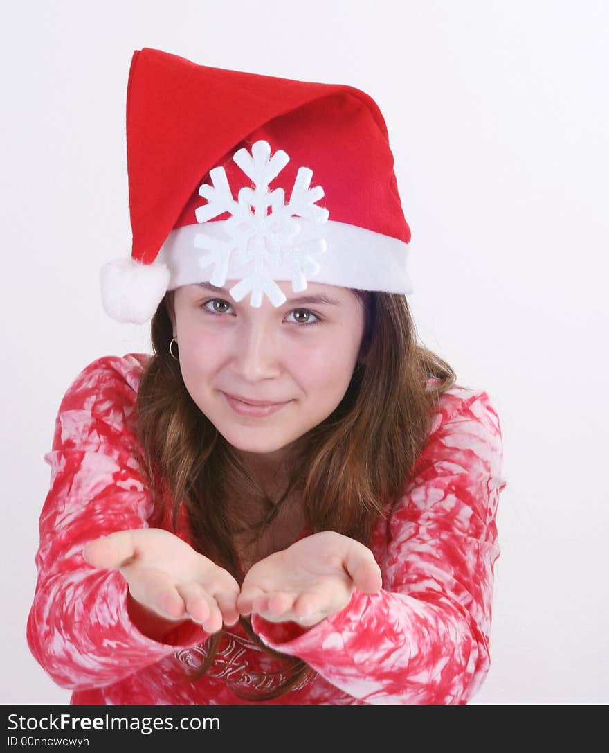 A portrait of a young teenager wearing a red Santa hat and red print top, holds out a large white snowflake in both hands in this studio setting. White background. A portrait of a young teenager wearing a red Santa hat and red print top, holds out a large white snowflake in both hands in this studio setting. White background.