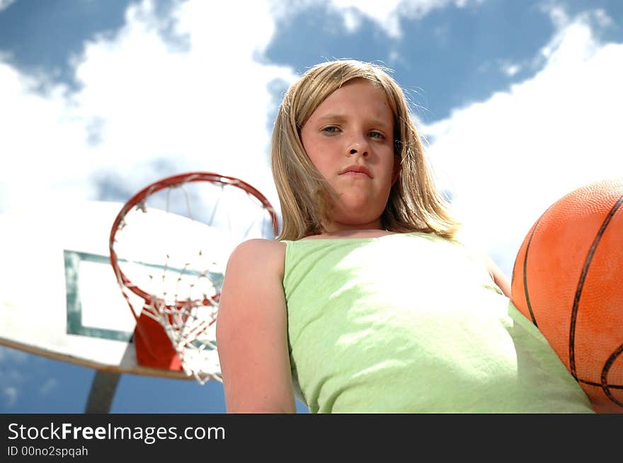 Young girl with basketball with sky and clouds