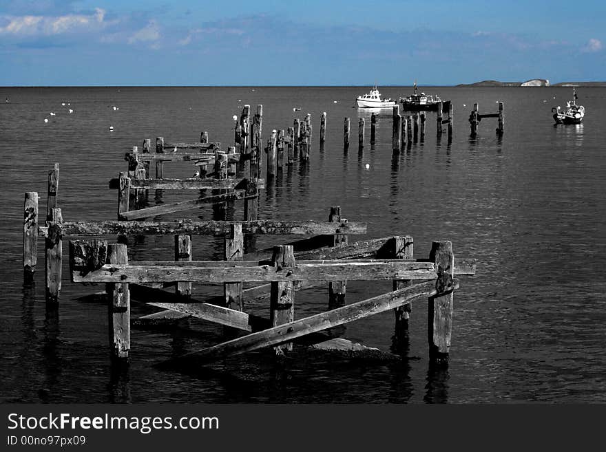 Old damaged wooden pier supports creating nice shape leading to boats. Old damaged wooden pier supports creating nice shape leading to boats