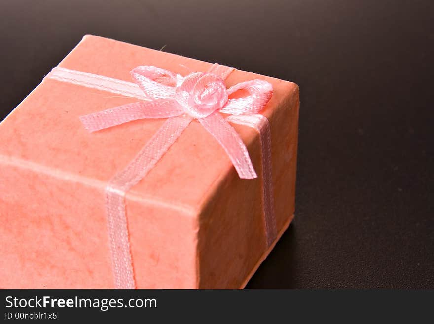 Pink gift box with ribbon on black isolated