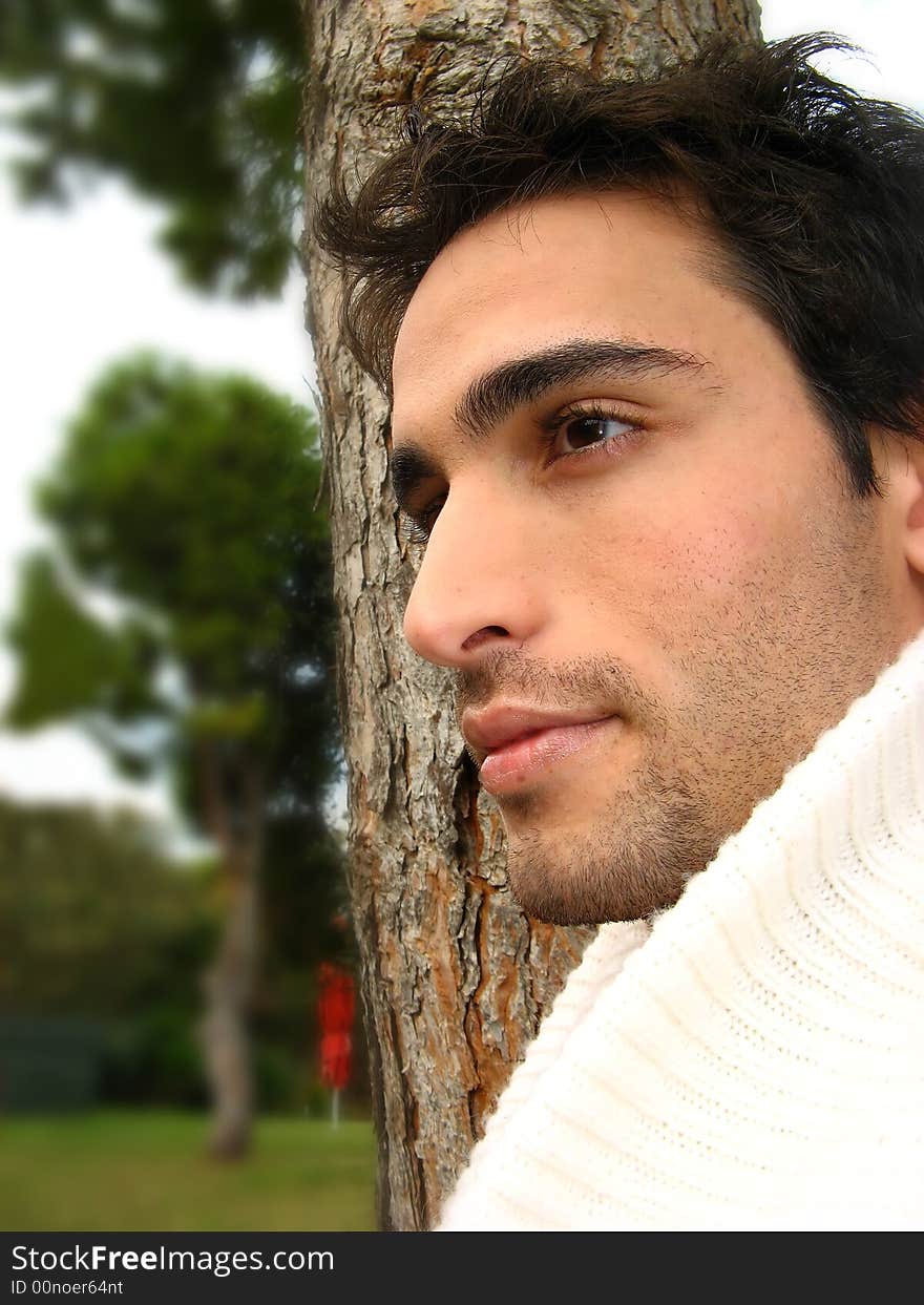 A young man side at the camera outdoors