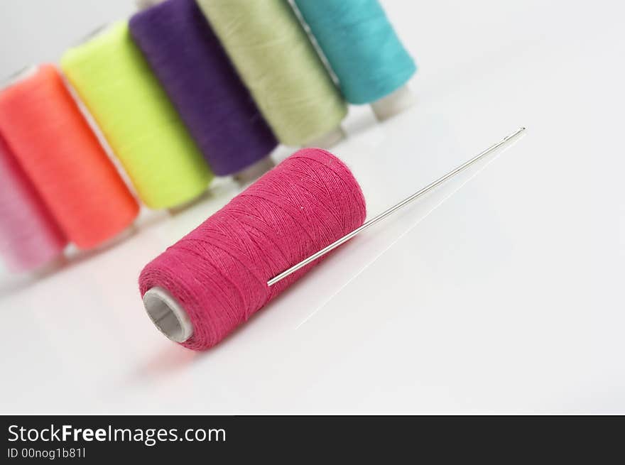 Colorful threads and needle, pink,orange yellow, purple green and blue threads