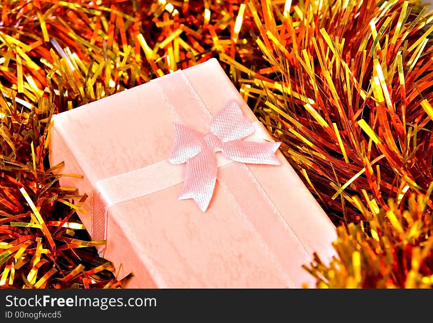 Pink Christmas gift with ribbon on colorful decorations. Pink Christmas gift with ribbon on colorful decorations