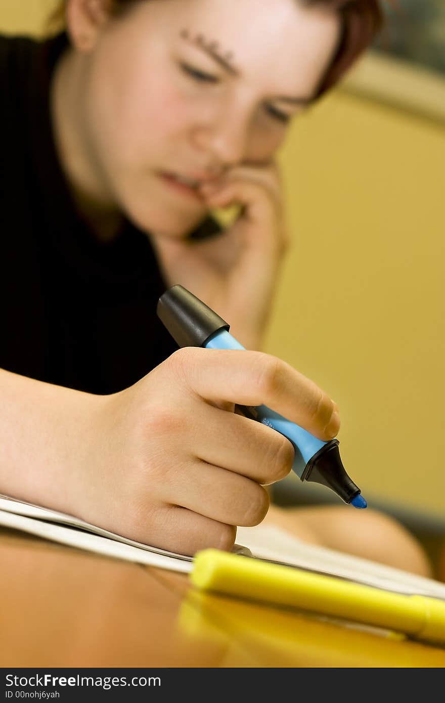 A pensive redhead student girl marking notes with a blue marker and biting her nails . Lit with three strobes, two ambient ones and one umbrelled from the left. A pensive redhead student girl marking notes with a blue marker and biting her nails . Lit with three strobes, two ambient ones and one umbrelled from the left.