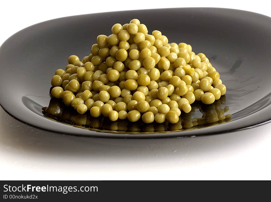 Fresh raw green peas in black plate