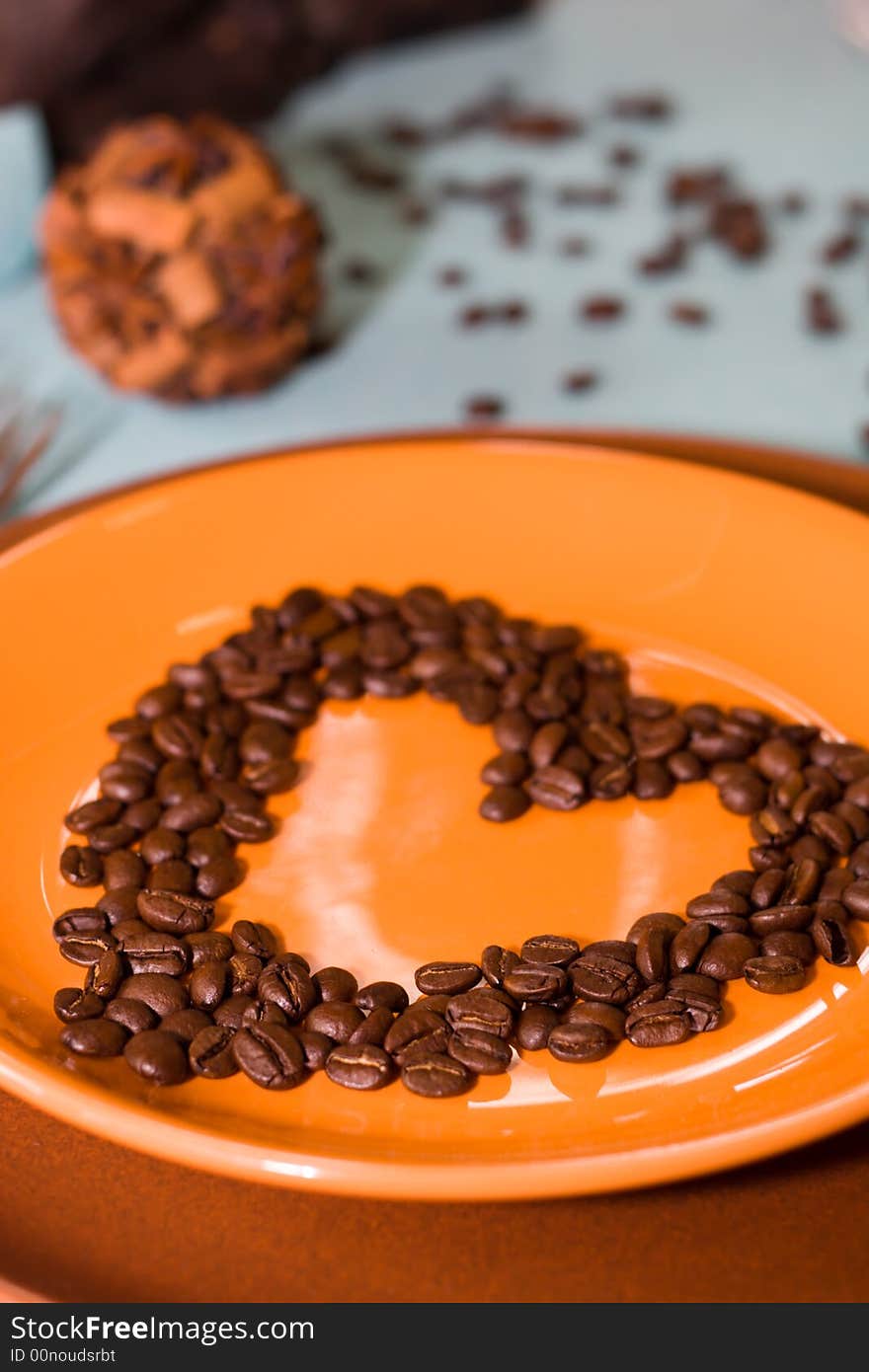 Coffee grains as a heart are laid out on a plate - Soft-focus view. Coffee grains as a heart are laid out on a plate - Soft-focus view.