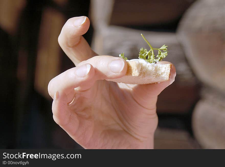 Small part of a sandwich with a parsley in a female hand on a background of a wooden wall. Small part of a sandwich with a parsley in a female hand on a background of a wooden wall