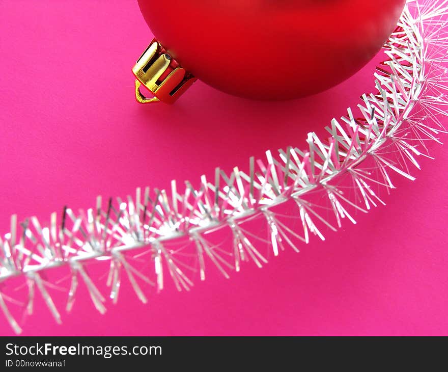 Christmas design with red bauble fragment and silver tinsel on pink background. Christmas design with red bauble fragment and silver tinsel on pink background