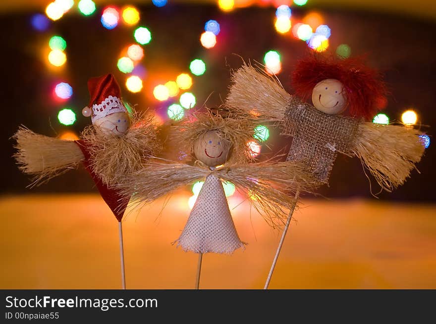 Three wooden figurines in lights of garland. Three wooden figurines in lights of garland