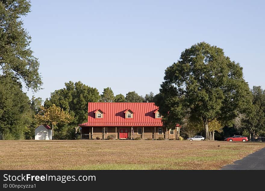 An old farmhouse on a long lot with a bright red roof. An old farmhouse on a long lot with a bright red roof