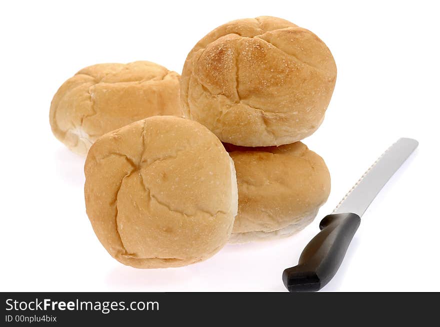 Fresh baked rolls and bread knife on white background.