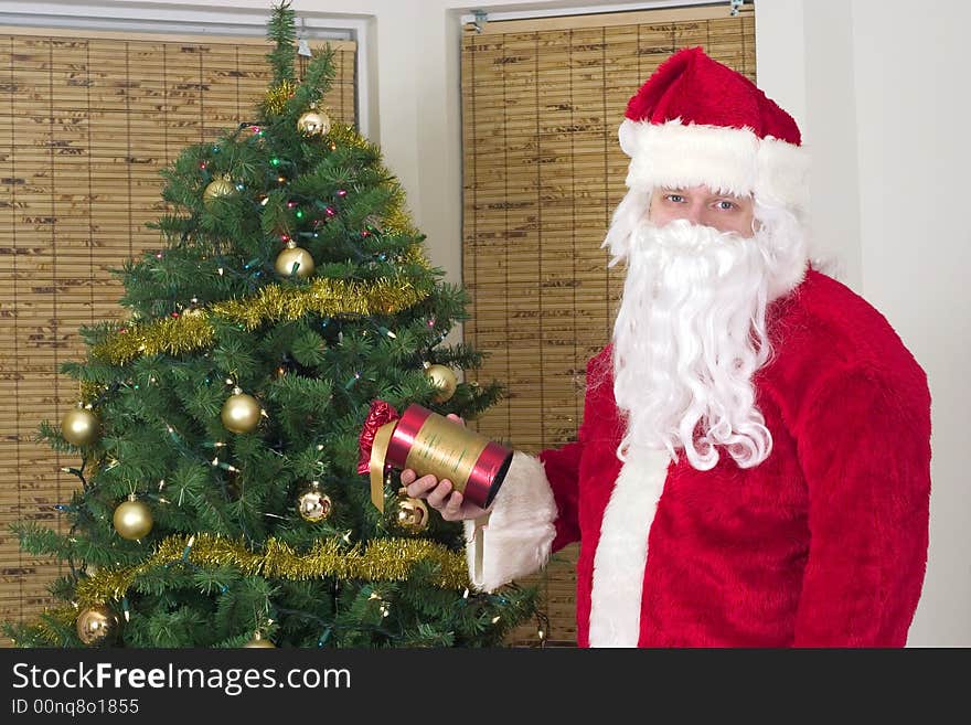 Santa Claus with gift near christmas tree. Santa Claus with gift near christmas tree