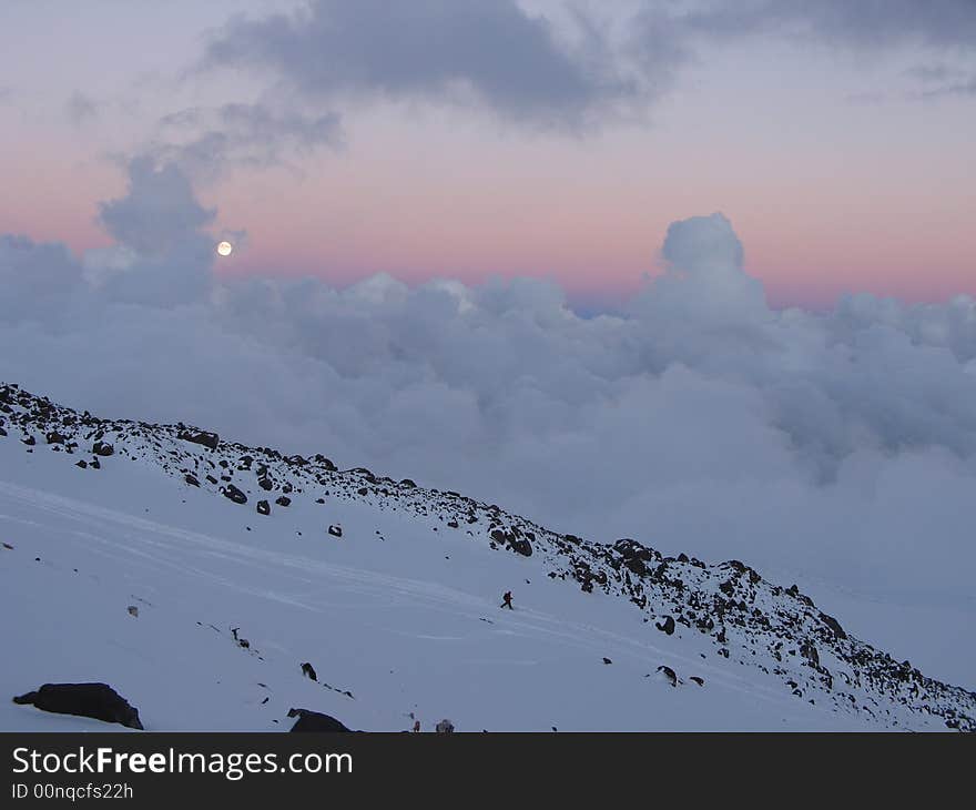 The moon, clouds and a small figure of the mountaineer which climbs down a mountain. The moon, clouds and a small figure of the mountaineer which climbs down a mountain