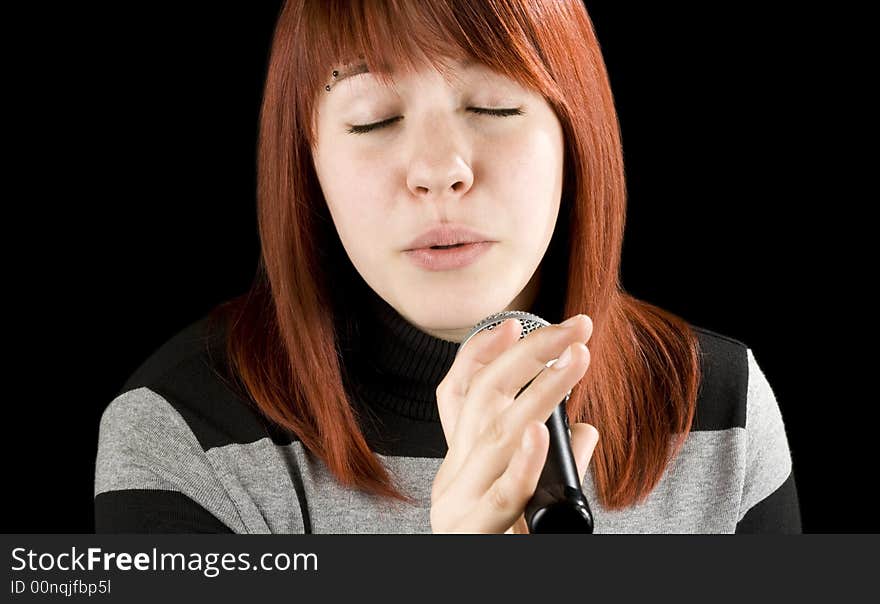 Redhead girl singing karaoke with a microphone. Sweet face.

Studio shot.