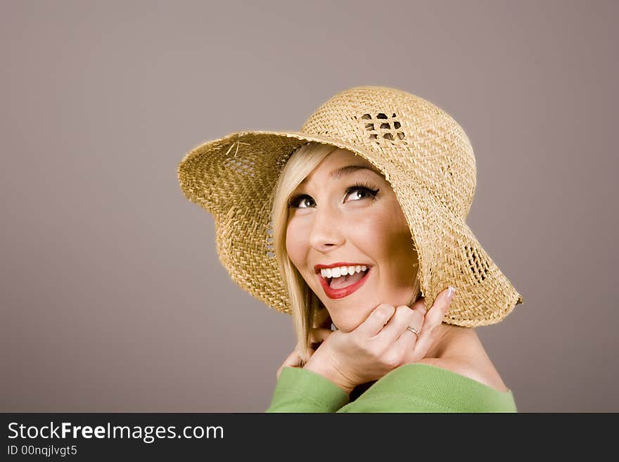 A beautiful fashion model smiling in a straw hat. A beautiful fashion model smiling in a straw hat