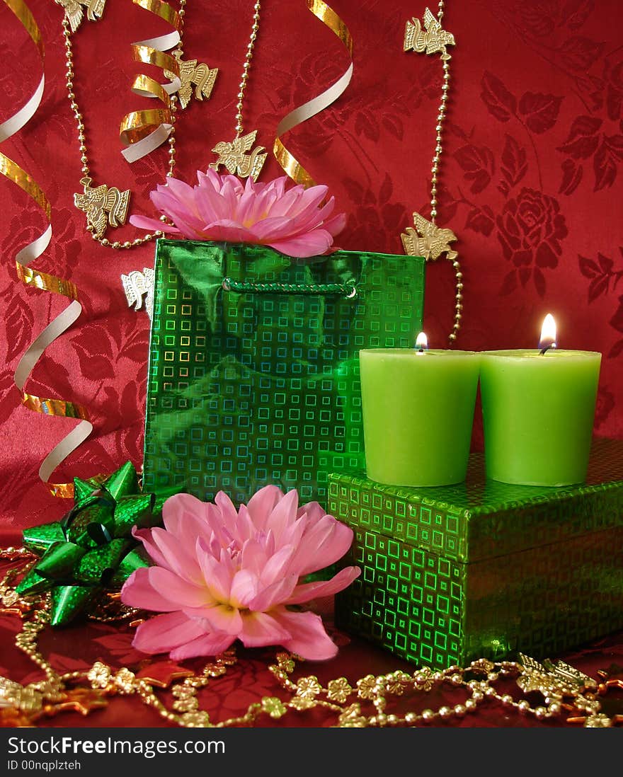 Celebration table (candles, flowers and gift on red background)