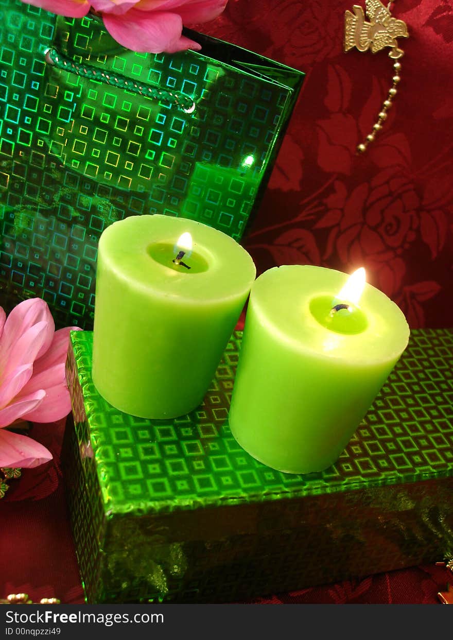 Celebration table (candles, flowers and gift on red background)