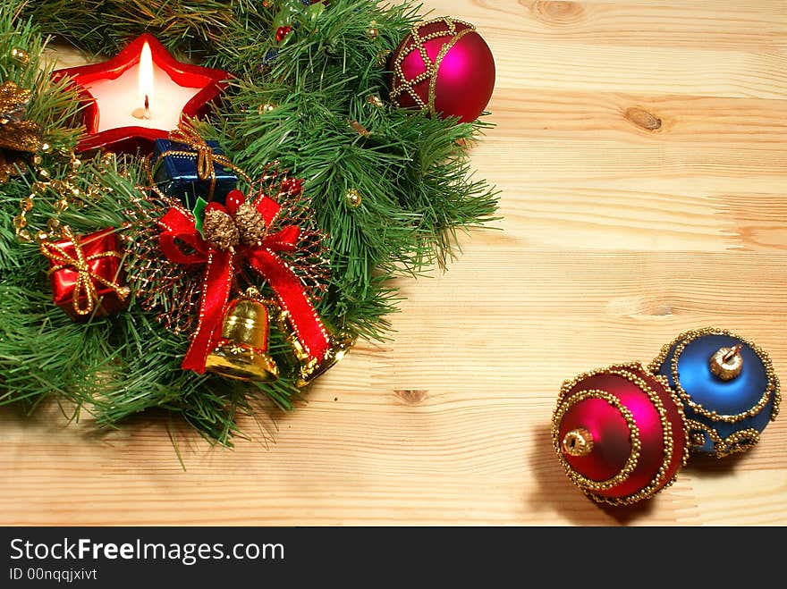 Green Xmas wreath with a candle and different decorations against wooden desk. Green Xmas wreath with a candle and different decorations against wooden desk