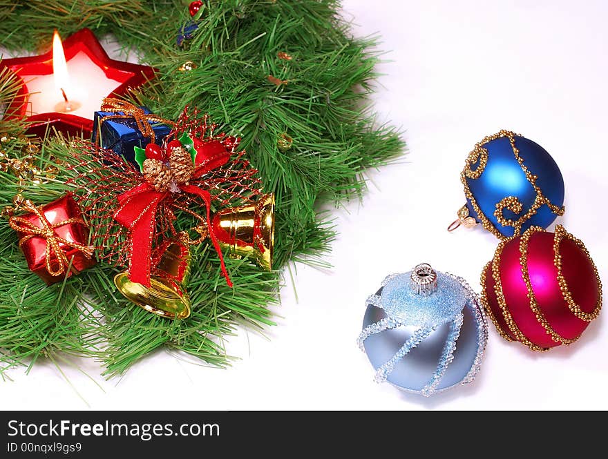 Isolated green Xmas wreath with a candle and different decorations against white background