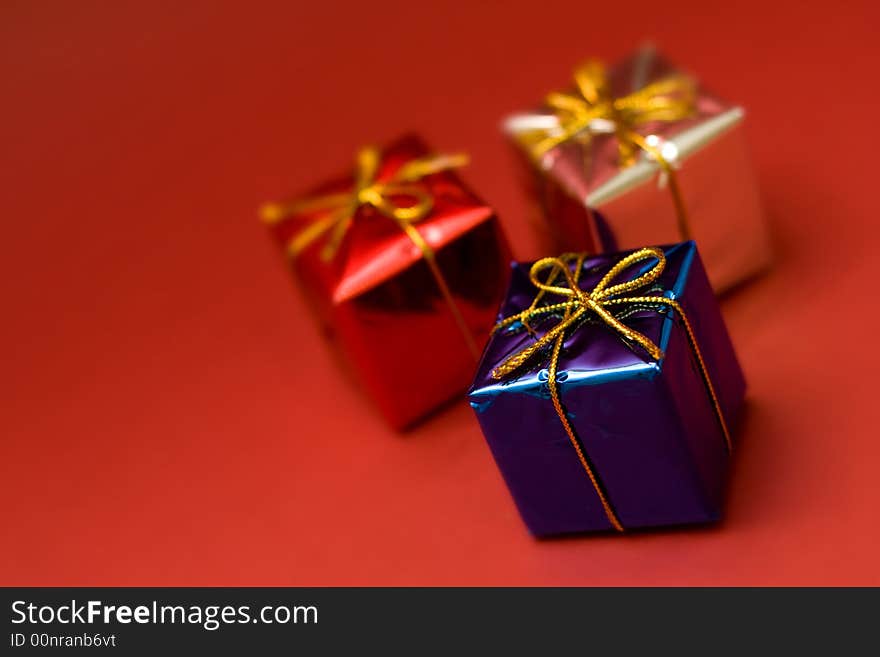 Little boxes with gifts on red background. Low DOF, copy space on left