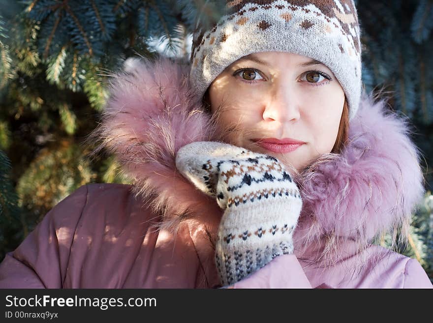 Beautiful girl in hat and mittens in snow-covered evergreens and rays of sun. Beautiful girl in hat and mittens in snow-covered evergreens and rays of sun