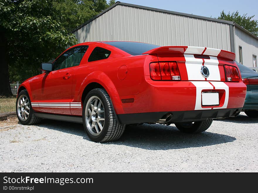 2007 Ford Mustang Shelby Cobra, GT 500, rear view. Red automobile with white racing stripes. 2007 Ford Mustang Shelby Cobra, GT 500, rear view. Red automobile with white racing stripes.