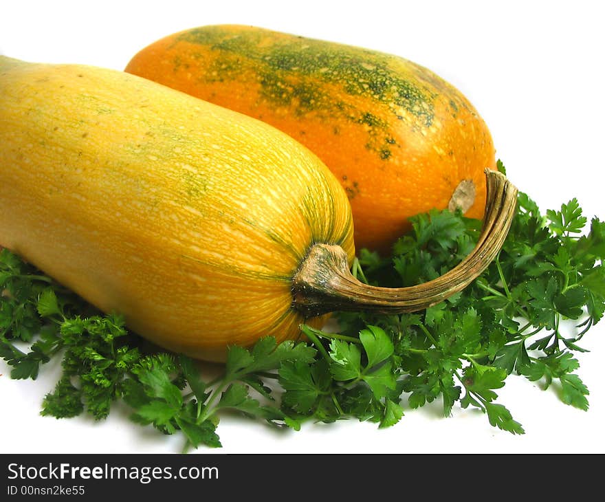 Yellow summer squashes and greens on white background